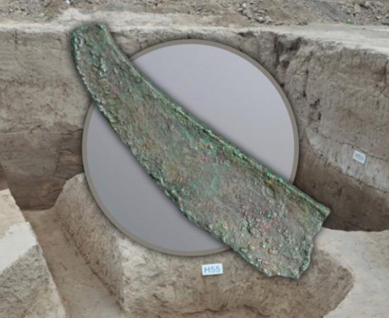 A broken bronze dagger-axe from the Jiangliu burial site, Shaanxi Province, with background of the excavation.