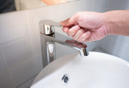 Hand turning off water faucet on bathroom sink